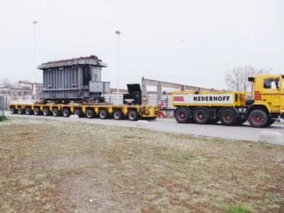 Transport van een transformator met een zwaar transporttrekker en platformwagen